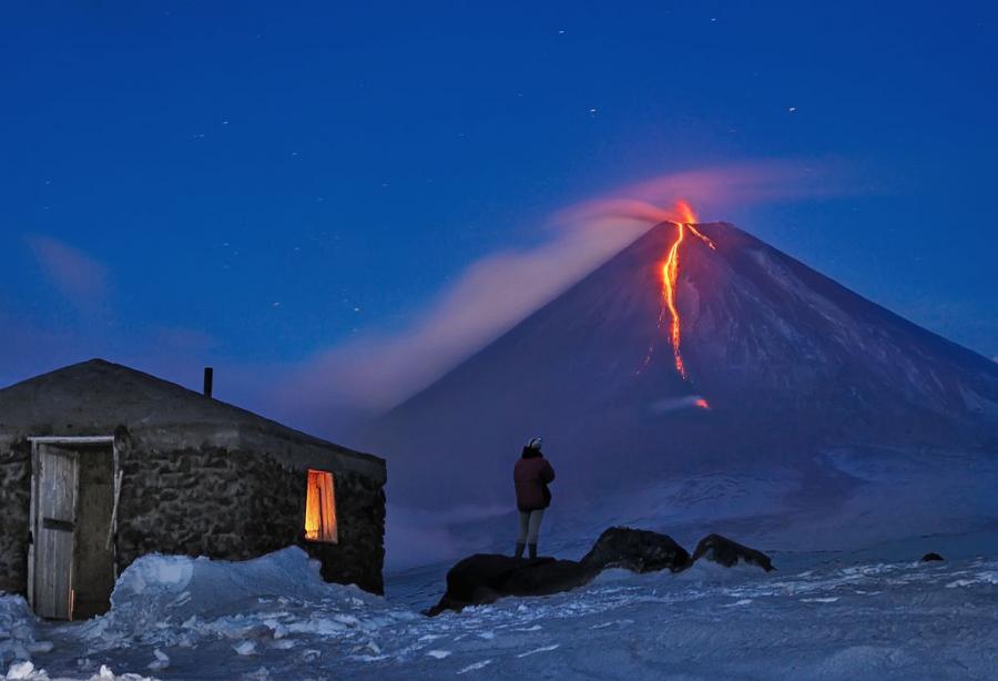 homme devant un volcan coulée de lave, nuit étoiles